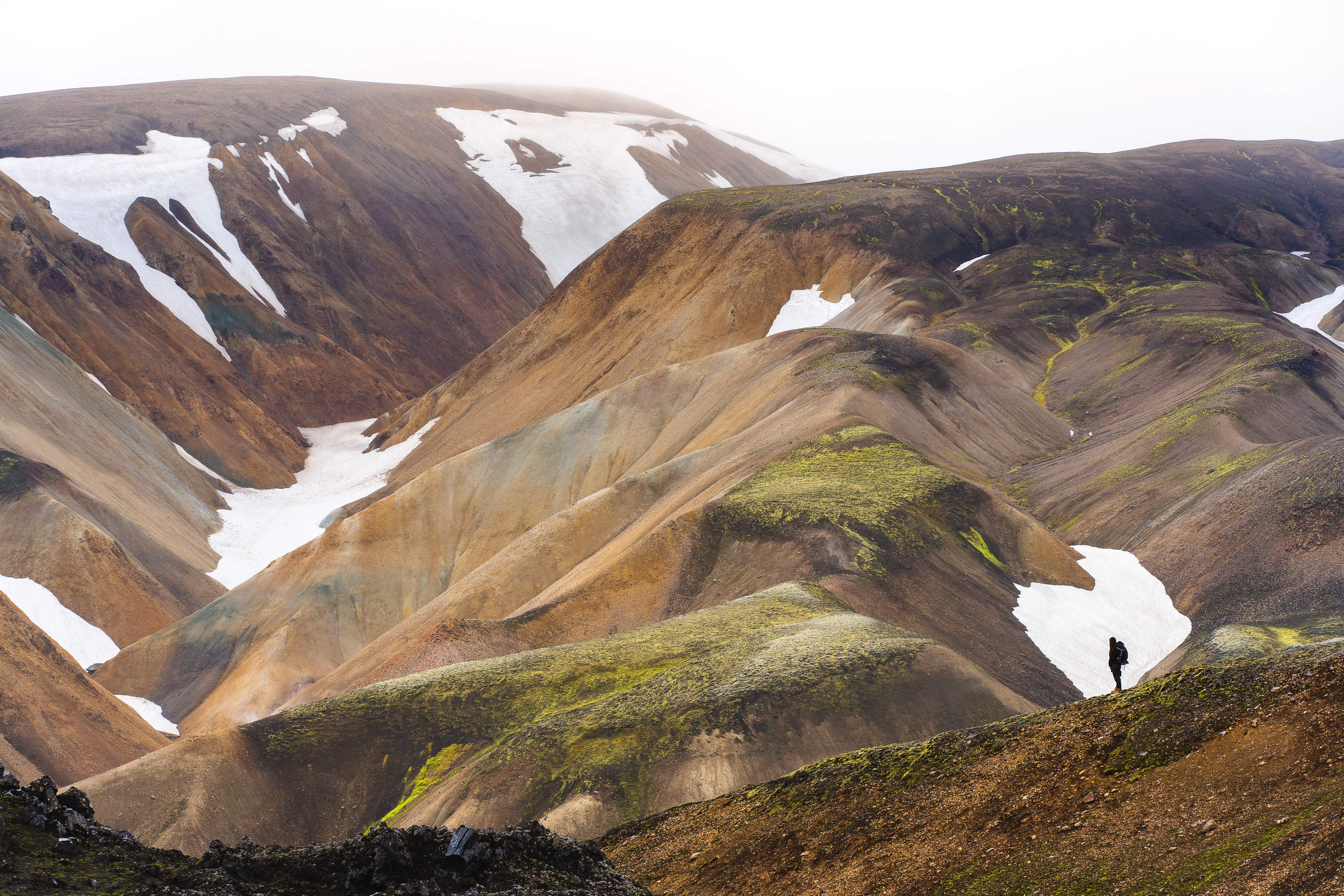 Snowy landscape of Icelandic hills with hiker standing to look at view