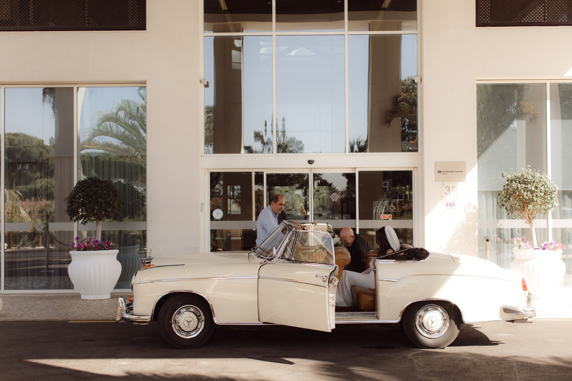Valet parked white vintage car in front of hotel doorway