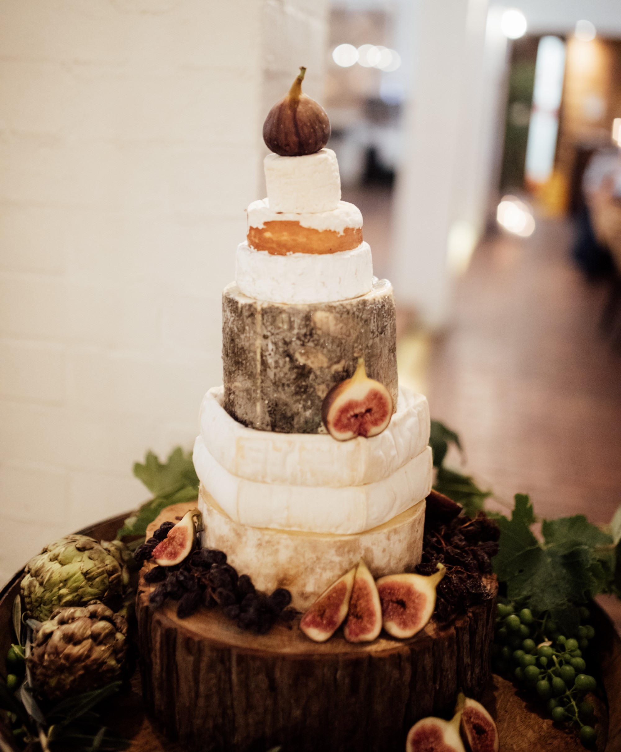 Wheels of cheese assembled in a cake-like manner with side of figs