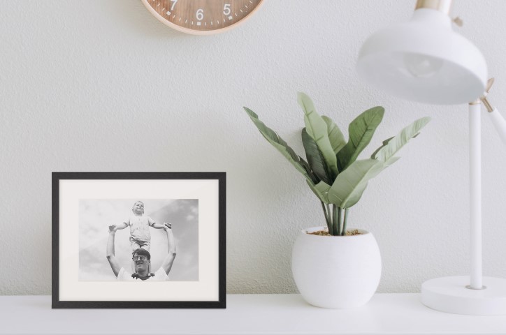 Picture frame on white table next to indoor potted plant