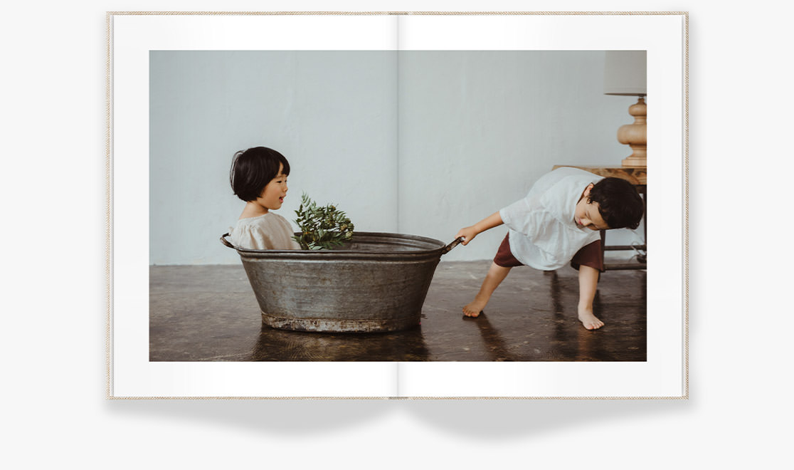 A photo of two sibling children playing in steel bathtub