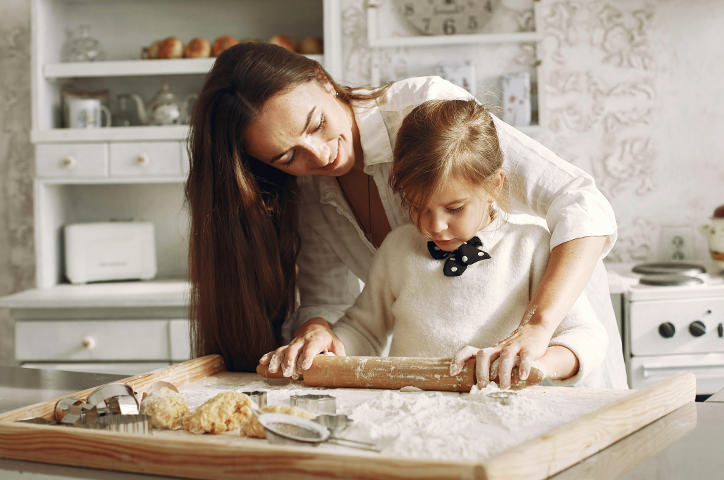 Mother and daughter rolling out dough