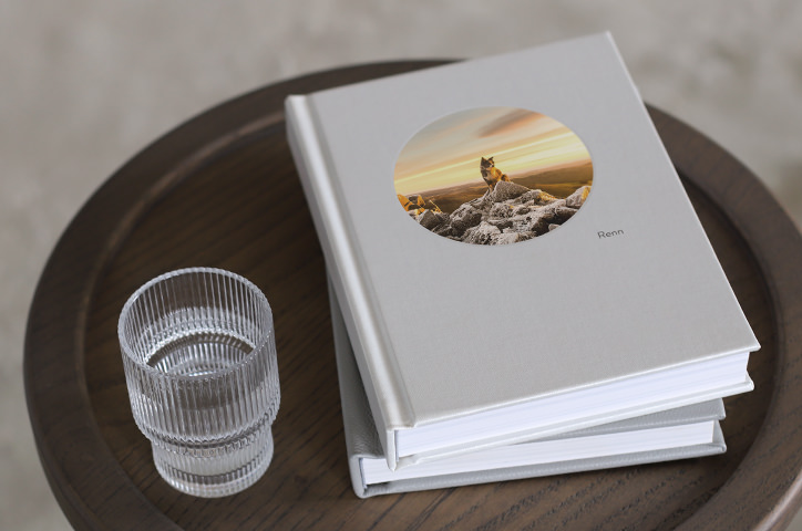 Woman and small dog read large square photo book with black and white dog photos