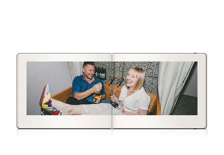 Landscape Moleskine photo book showing engaged couple laughing and toasting each other while sitting in wooden bathtub