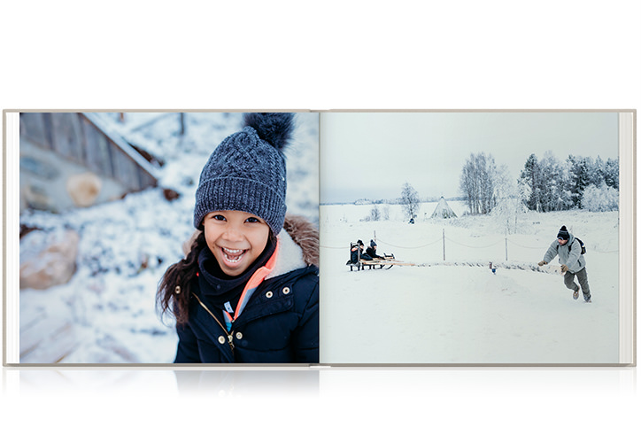 Girl smiles wide and sits with sibling on sled father pulls through snow