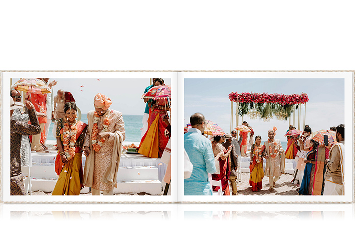 Indian newlywed couple walk down ailse on white stairs on beach in red and orange attire