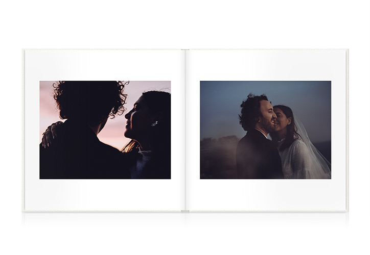 Open photo book with newlyweds together under dark pink and purple sunset sky