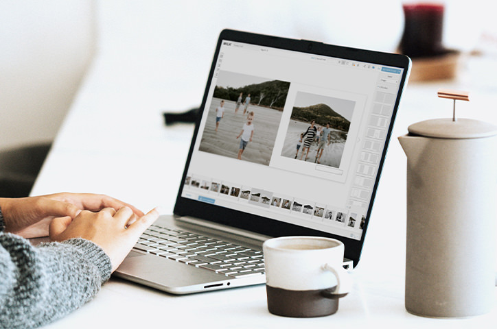 Woman in grey sweater using laptop displaying MILK Design Studio with coffee mug next to it.