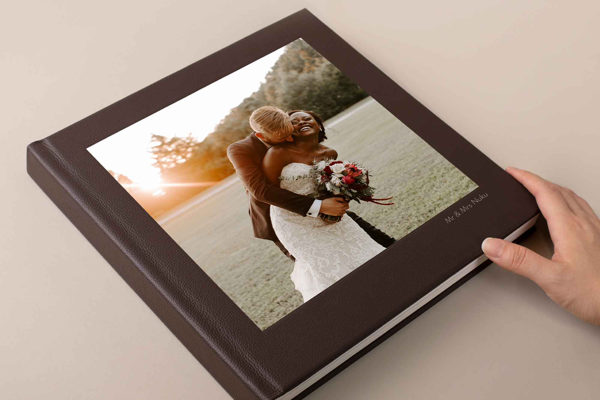 Hand on mocca colored premium leather photo album featuring a couple on their wedding day