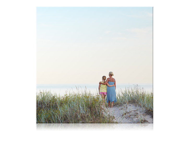 Tela quadrada de mãe e filha com braços ao redor um do outro na praia.