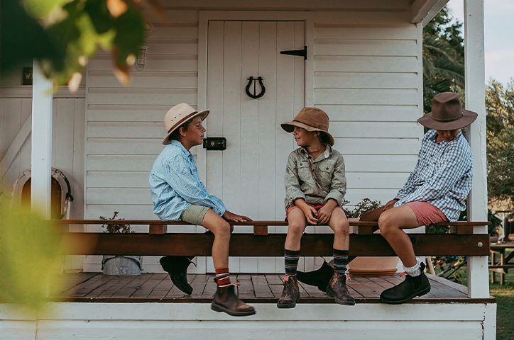 Three brothers in farm clothes sitting on the deck