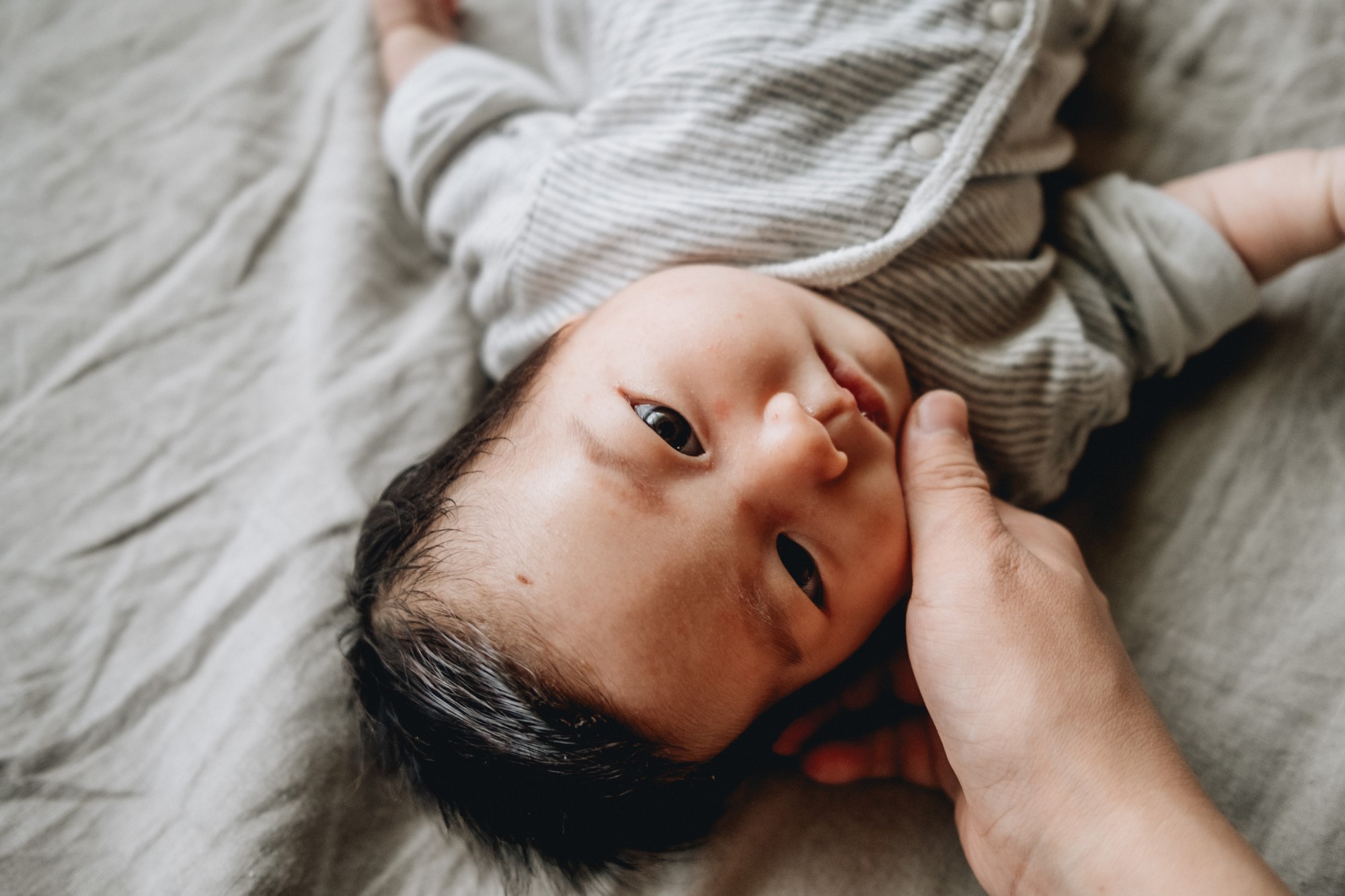 Parent touches baby face while baby is lying down