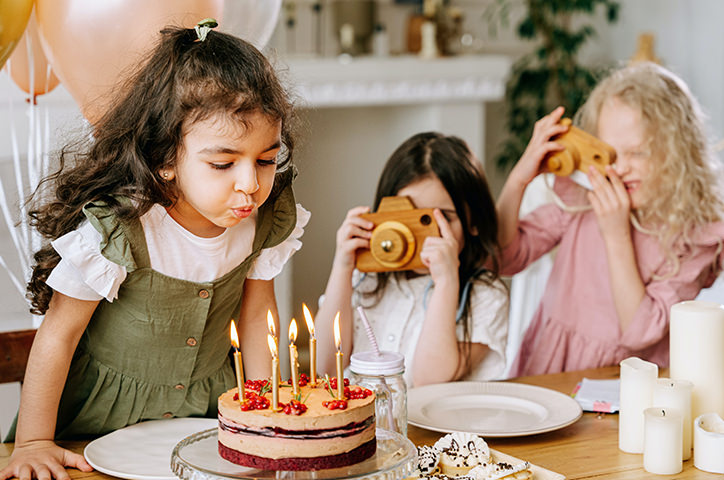 Child blowing out candles of birthday cake