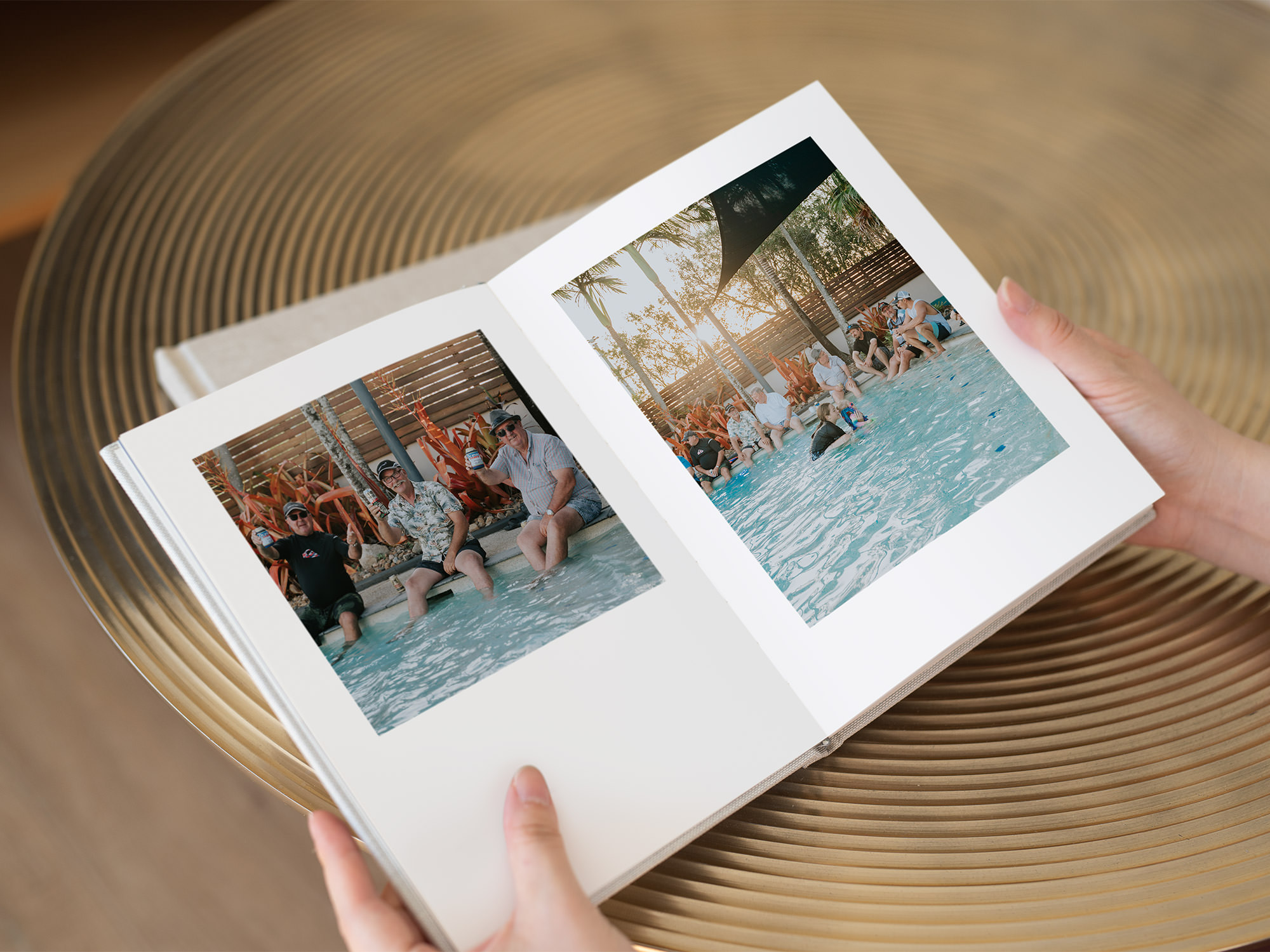 Portrait photo book being held and open to pictures of a pool party with men sitting around pool