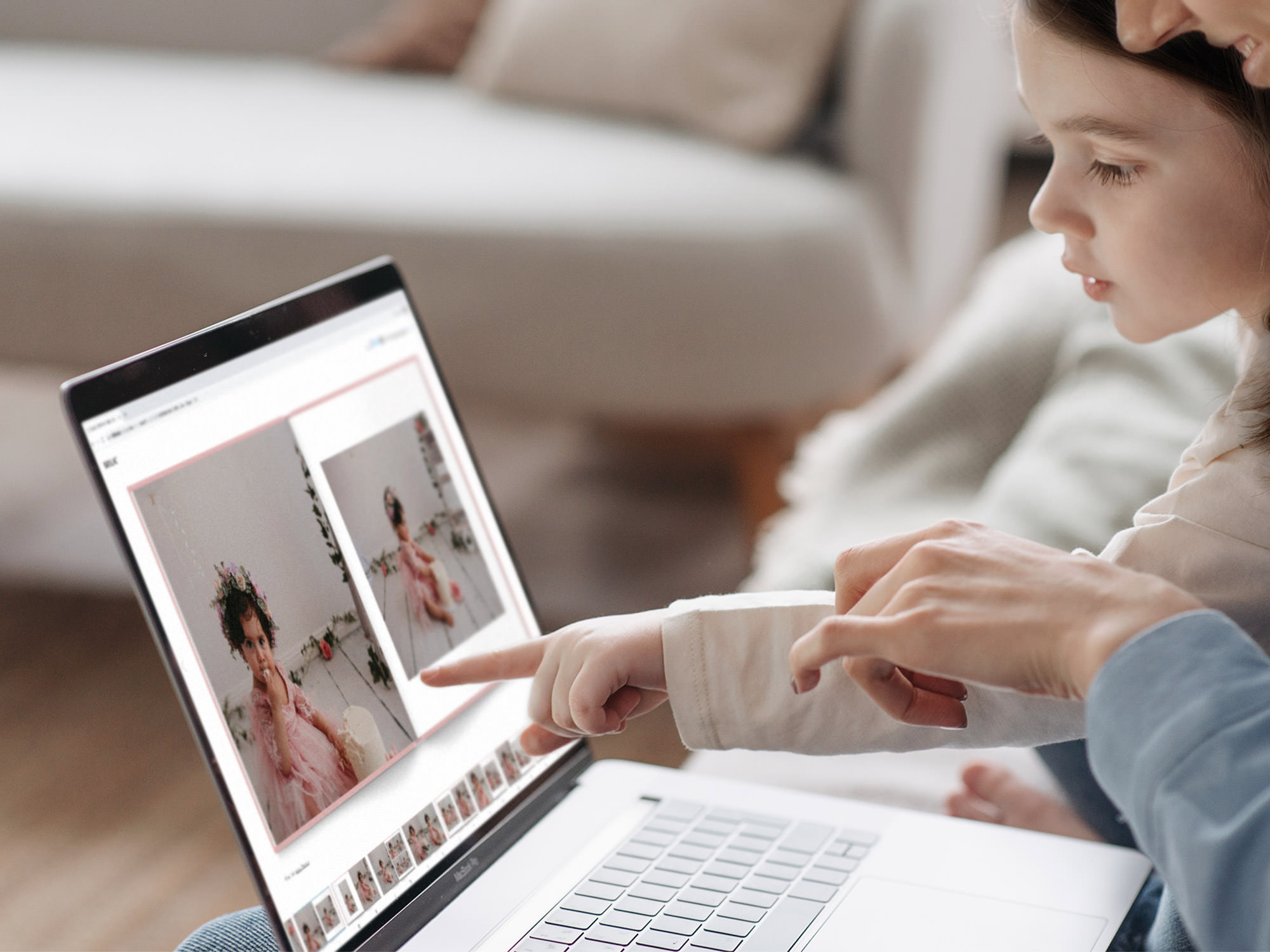 Mother and daughter look at photos of young girl in pink dress in a photo book on the laptop