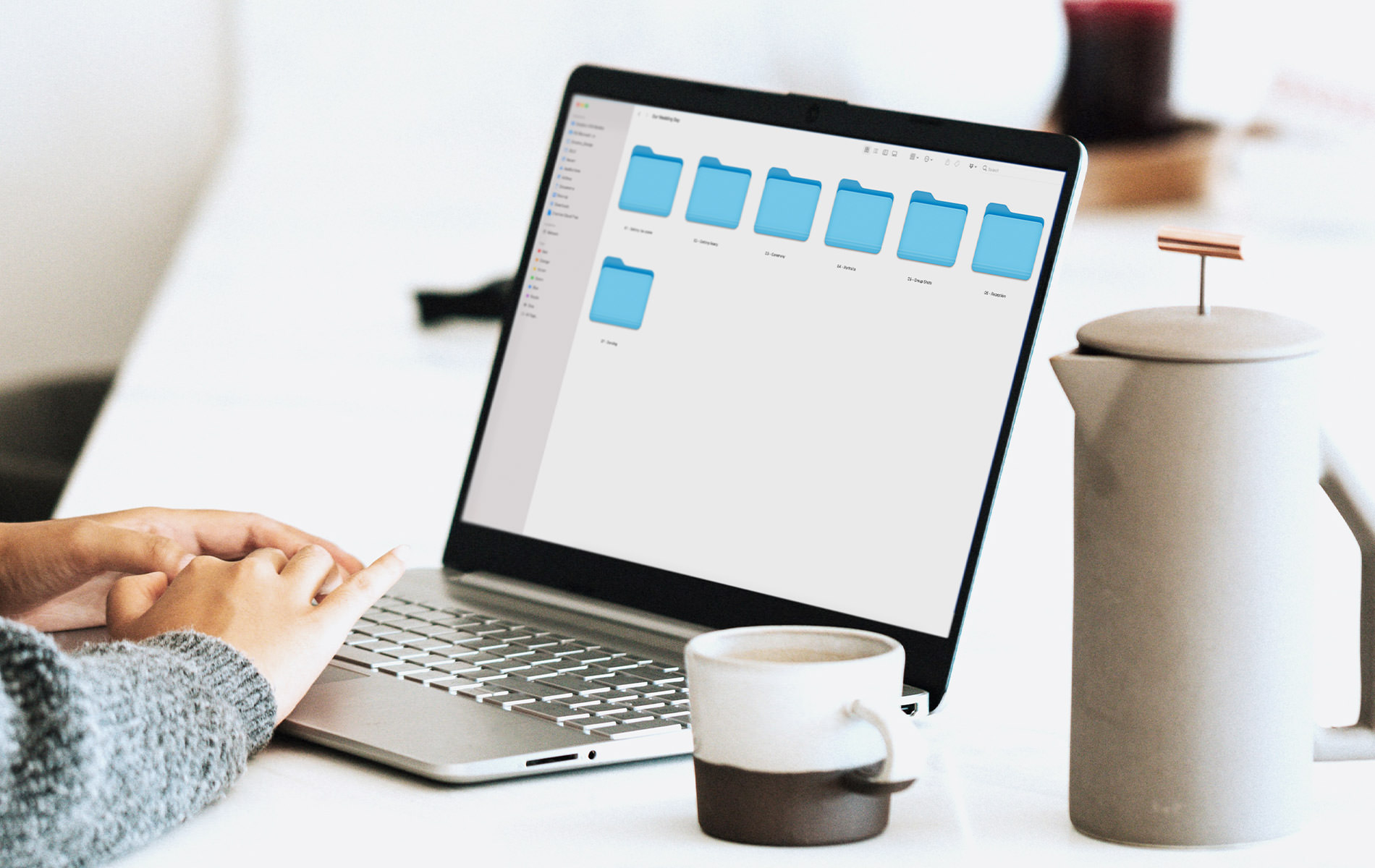 Laptop showing MILK Design Studio next to coffee press