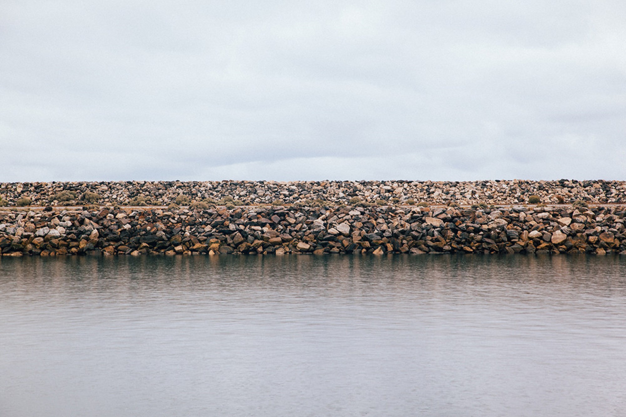 Man made stone ocean wall barrier under cloudy sky