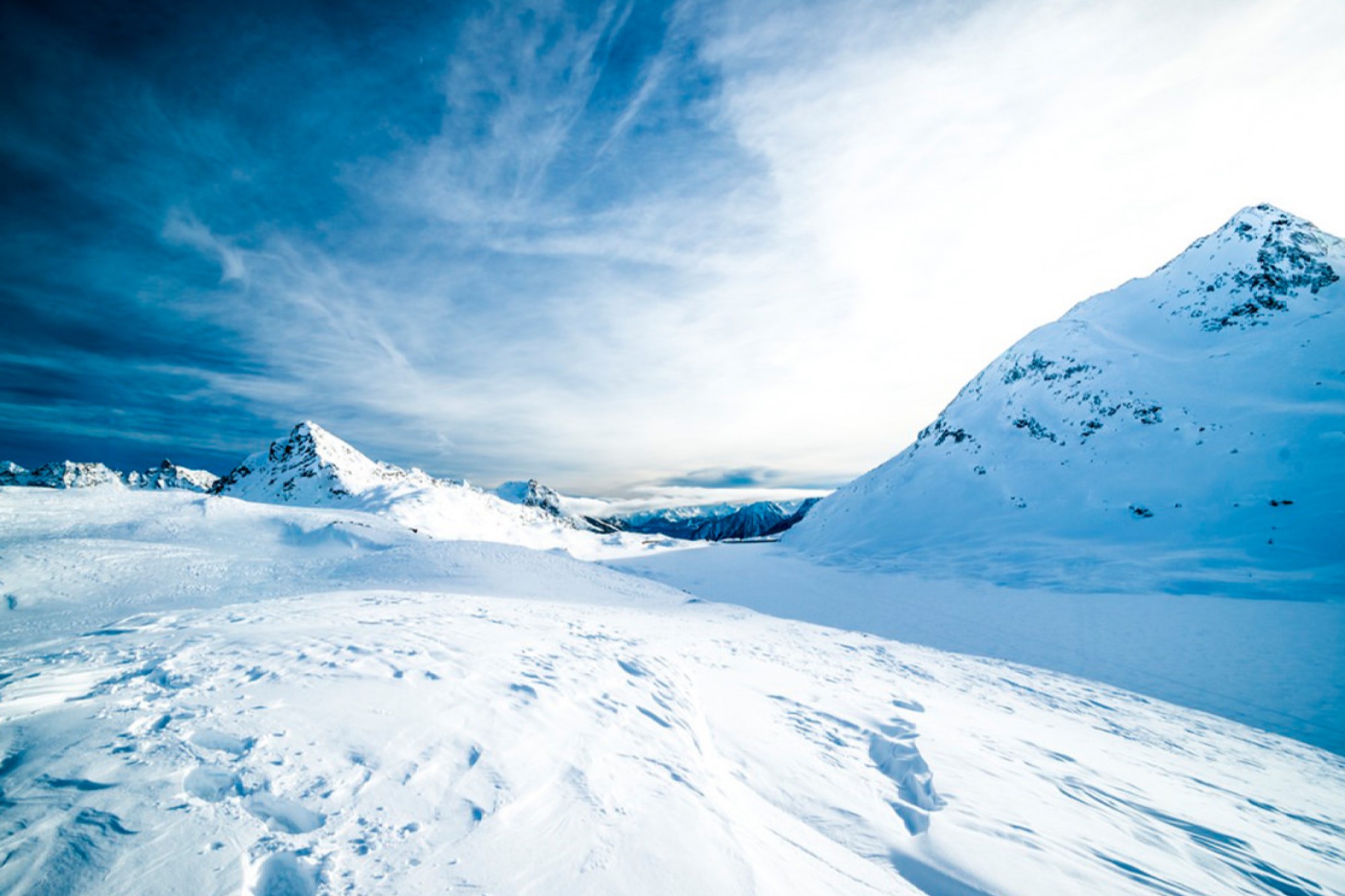 Landscape of snowy mountain flat area with windy blue skies