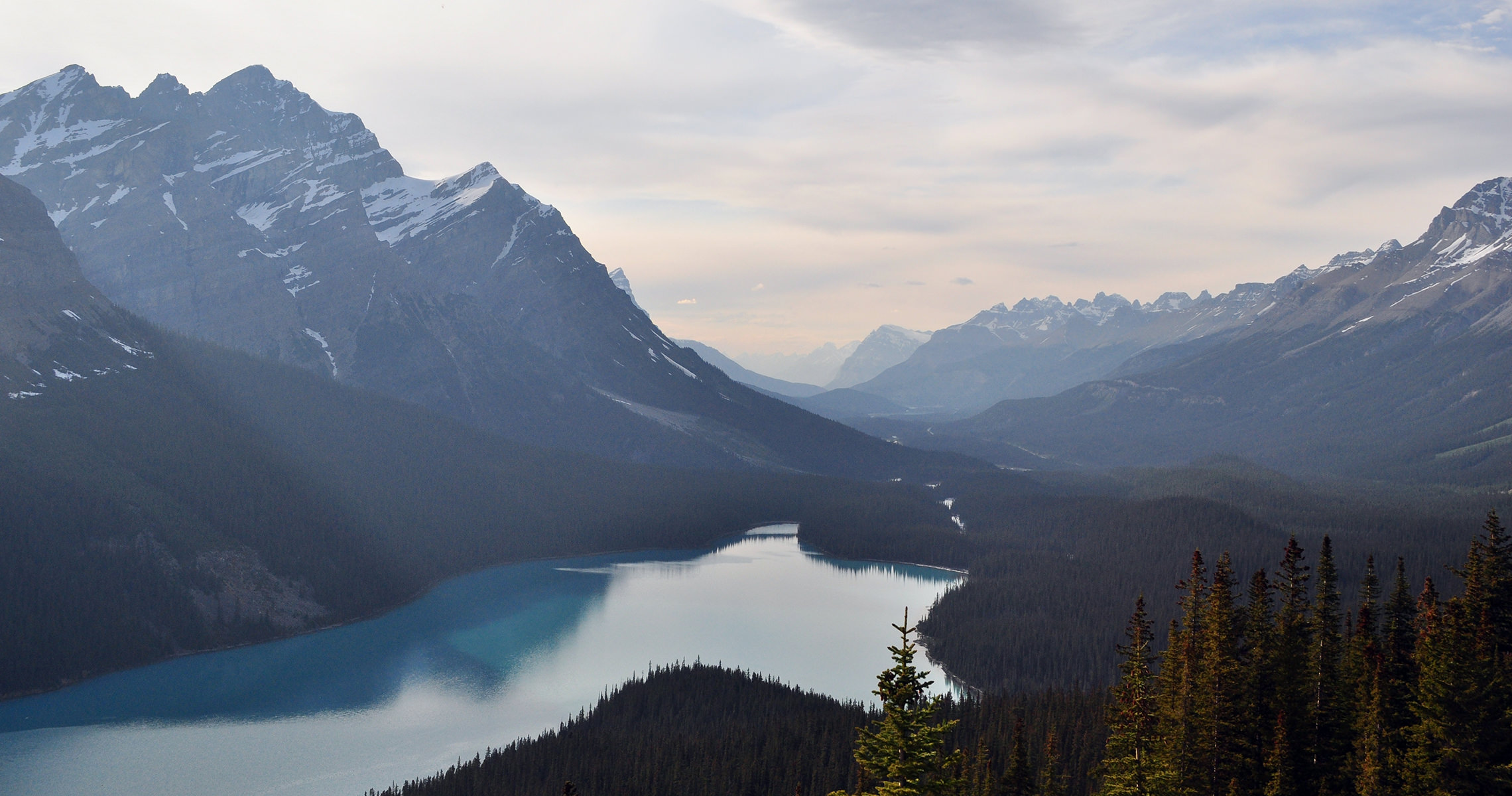View of lake with bordering mountains and forest on a beautiful cloudy day