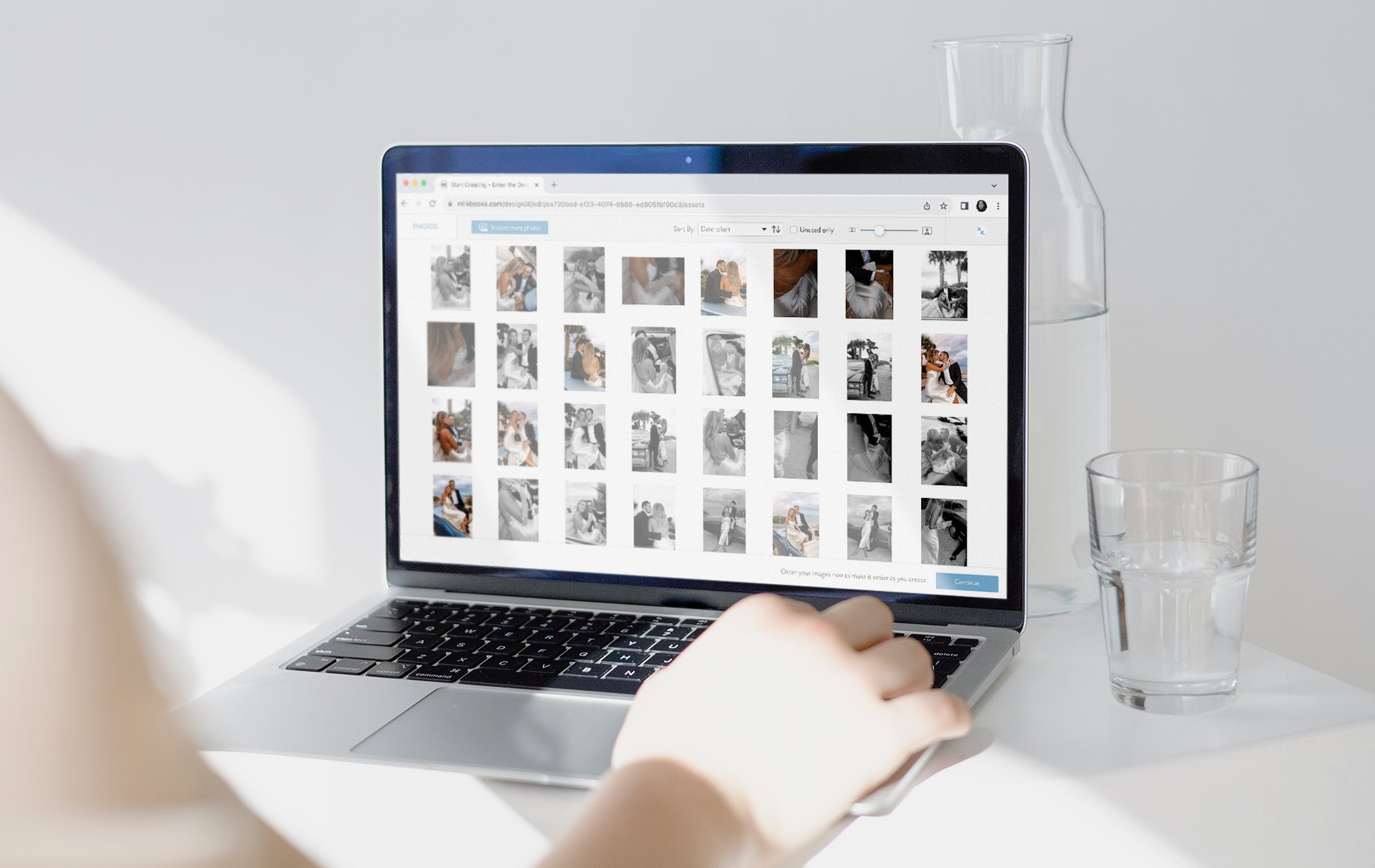 Laptop open on MILK Design Studio image library in white bedroom