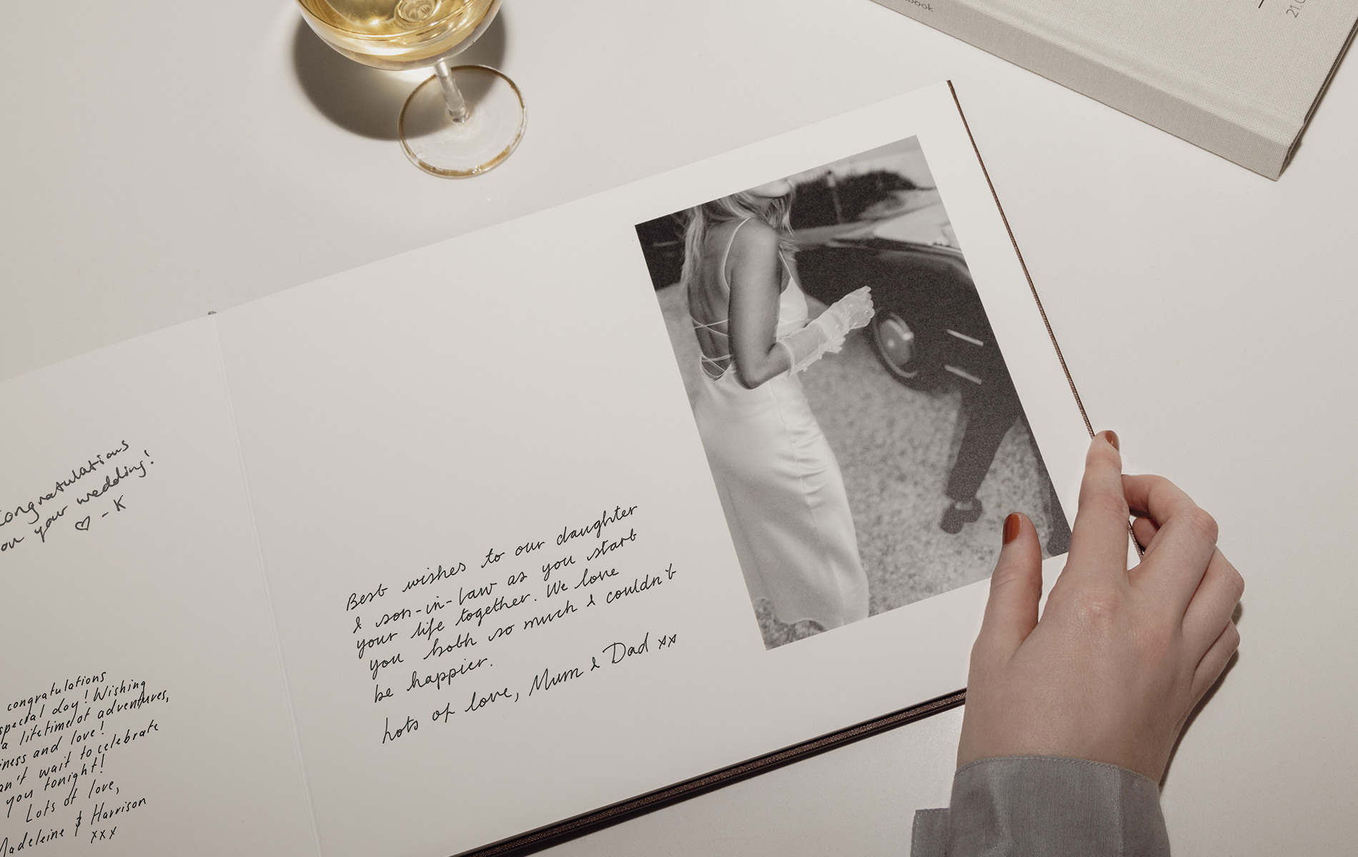 Flipping the pages of a Wedding Guest Book with handwritten messages inside and champagne glass next to book