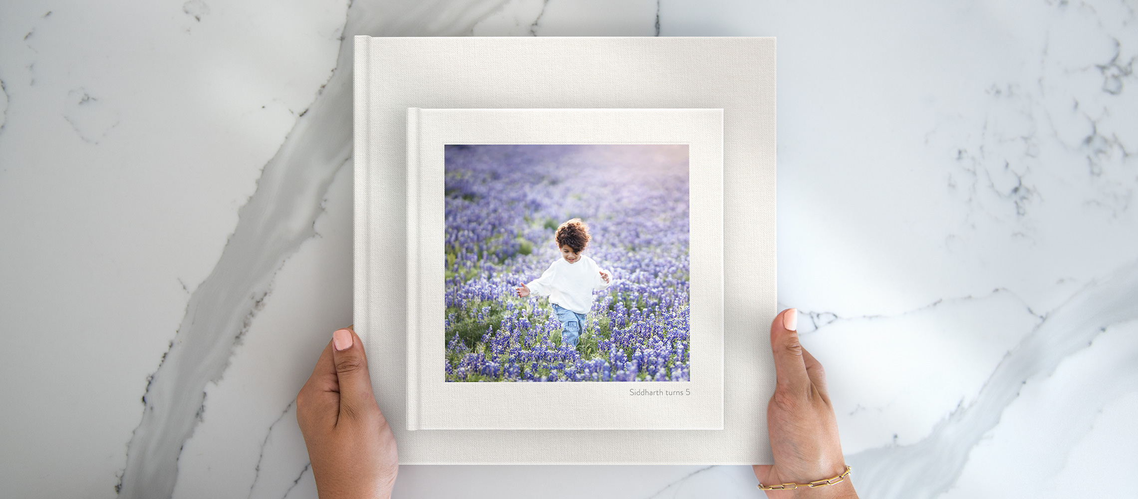 Holding two Square Premium Birthday Photo Albums with young boy on cover