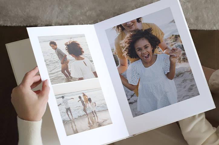 Woman holding a photo album of a family day at the beach