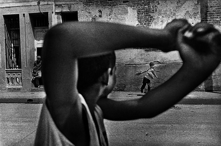 Monochrome photo of boys playing baseball on a street in Cuba
