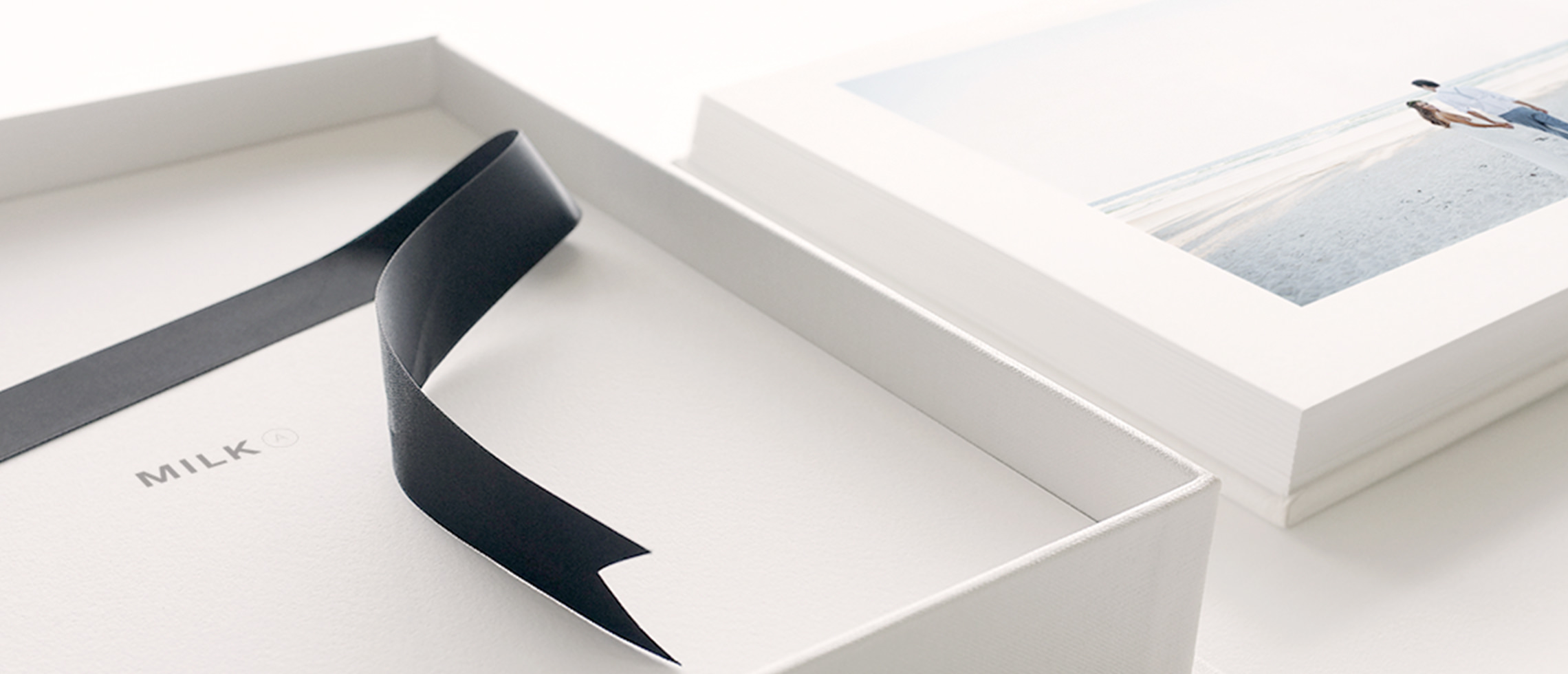 Grande plano sobre uma caixa de apresentação de MILK e o álbum fotográfico que o acompanha.