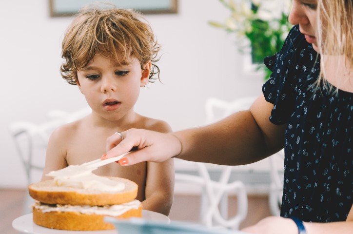 Young child and woman icing a cake