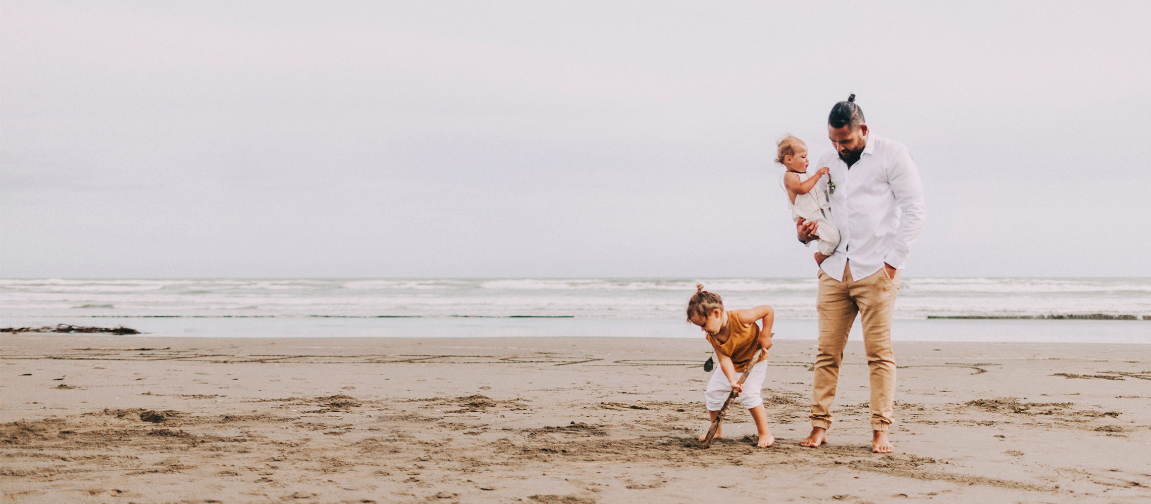O pai brincando com seus dois filhos na praia.