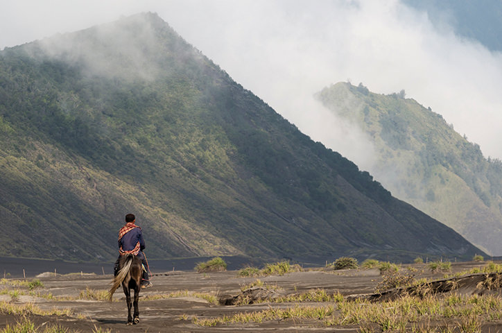 Man riding a horse through misty hills cape