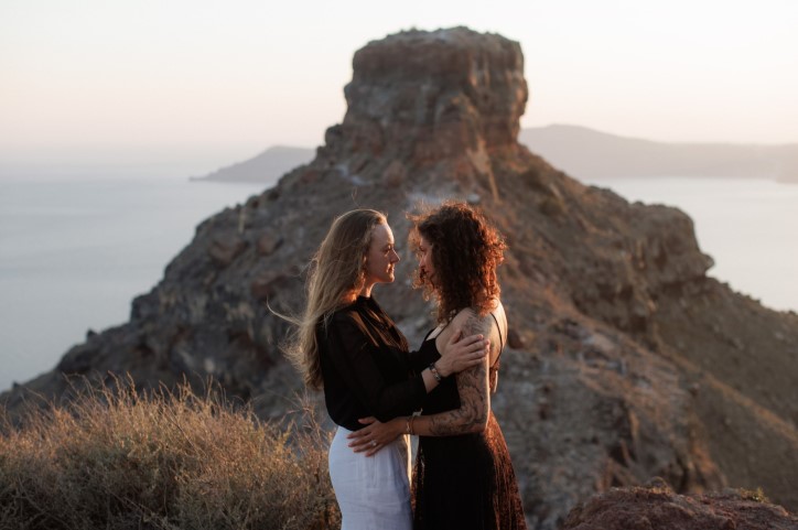 Engaged women couple face each other on clifftop in Athens Greece