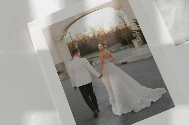 Newlywed couple holding hands walking together outside on pavement at sunset.