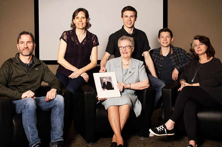 Family sitting in living room and presenting photo album.