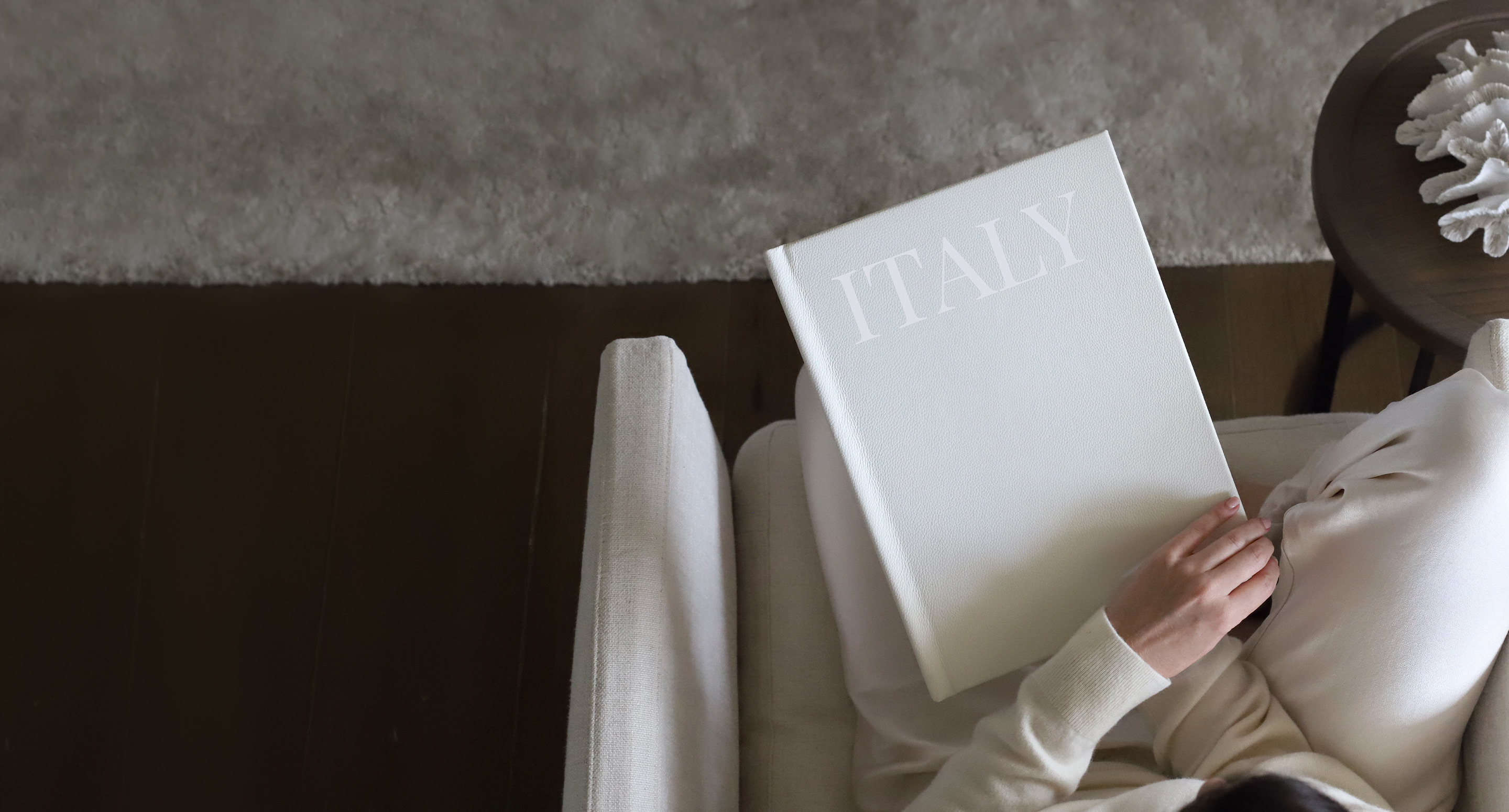 Woman seated looking at Large Premium Photo Album with 'Italy' UV printed in white on white linen cover.