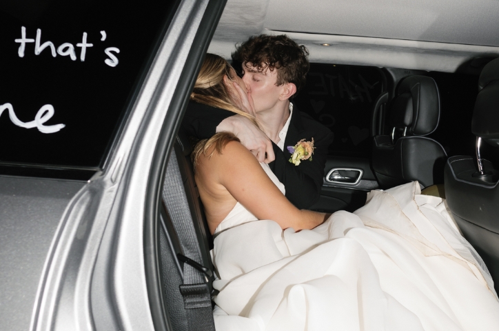 Couple kissing in car with white writing on windows.