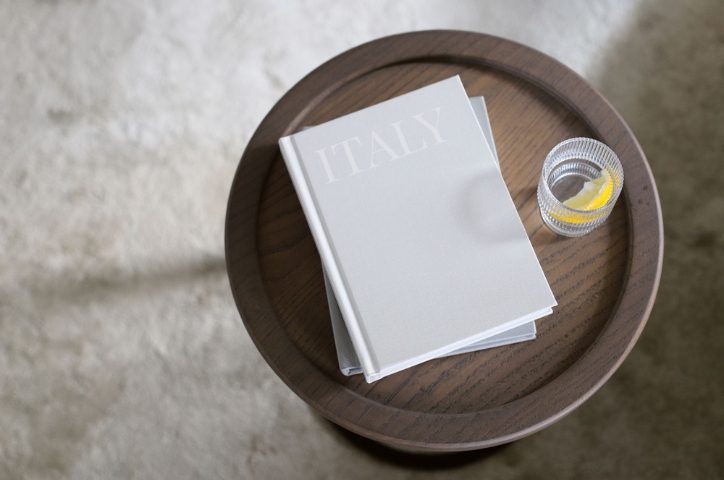 Photo of a portrait photo album on table featuring italic writing saying "Italy"