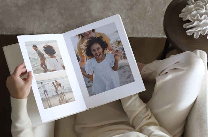 Seated woman holding an open MILK Premium Portrait Family Photo Album.