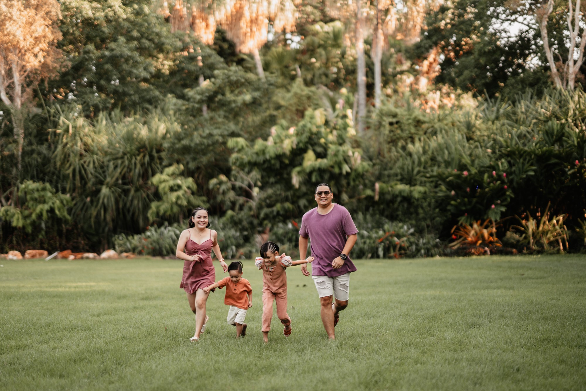 Family of four running towards camera smiling.