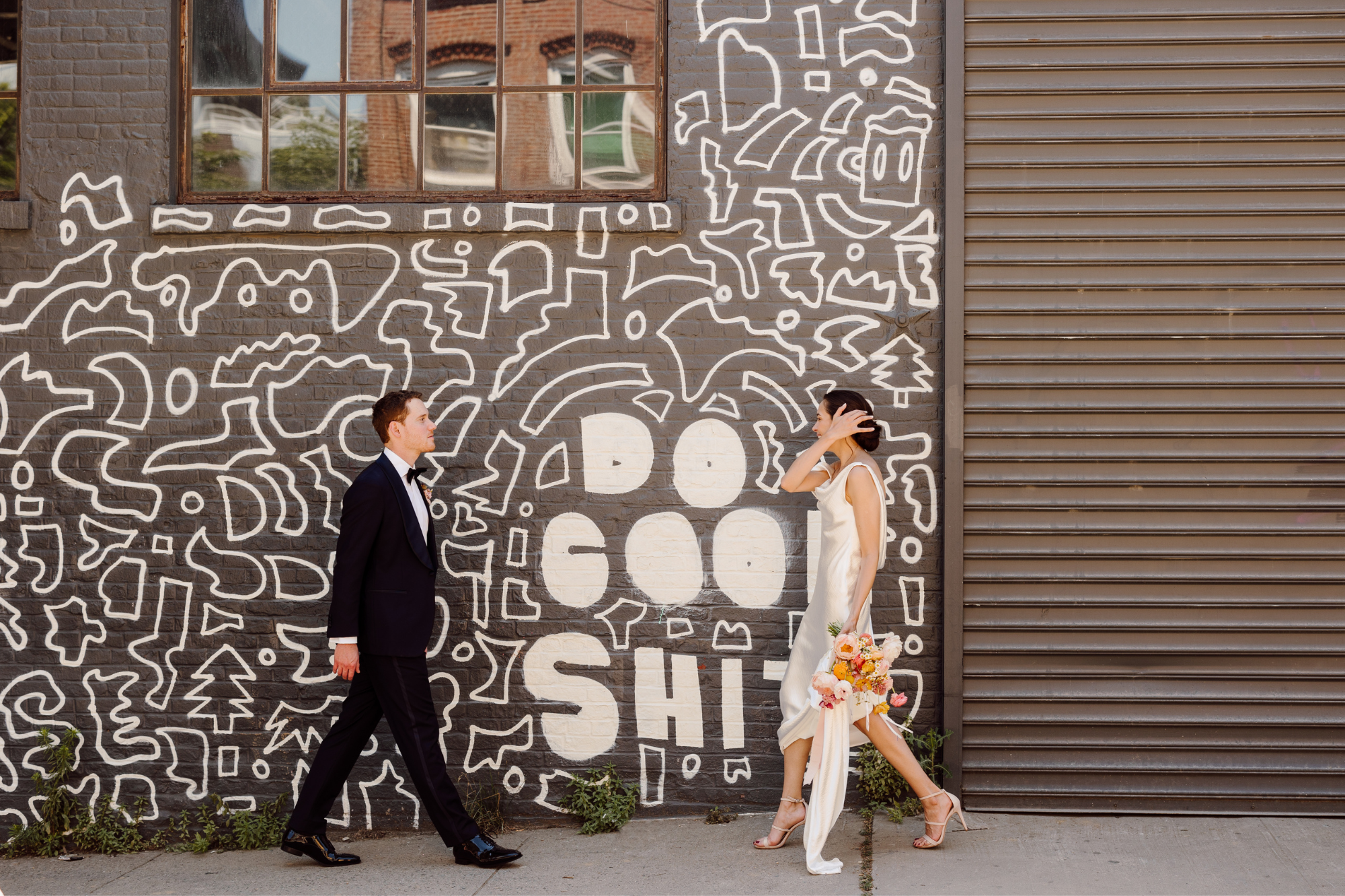 Bride and groom walk to each other in front of black and white graphic art street wall