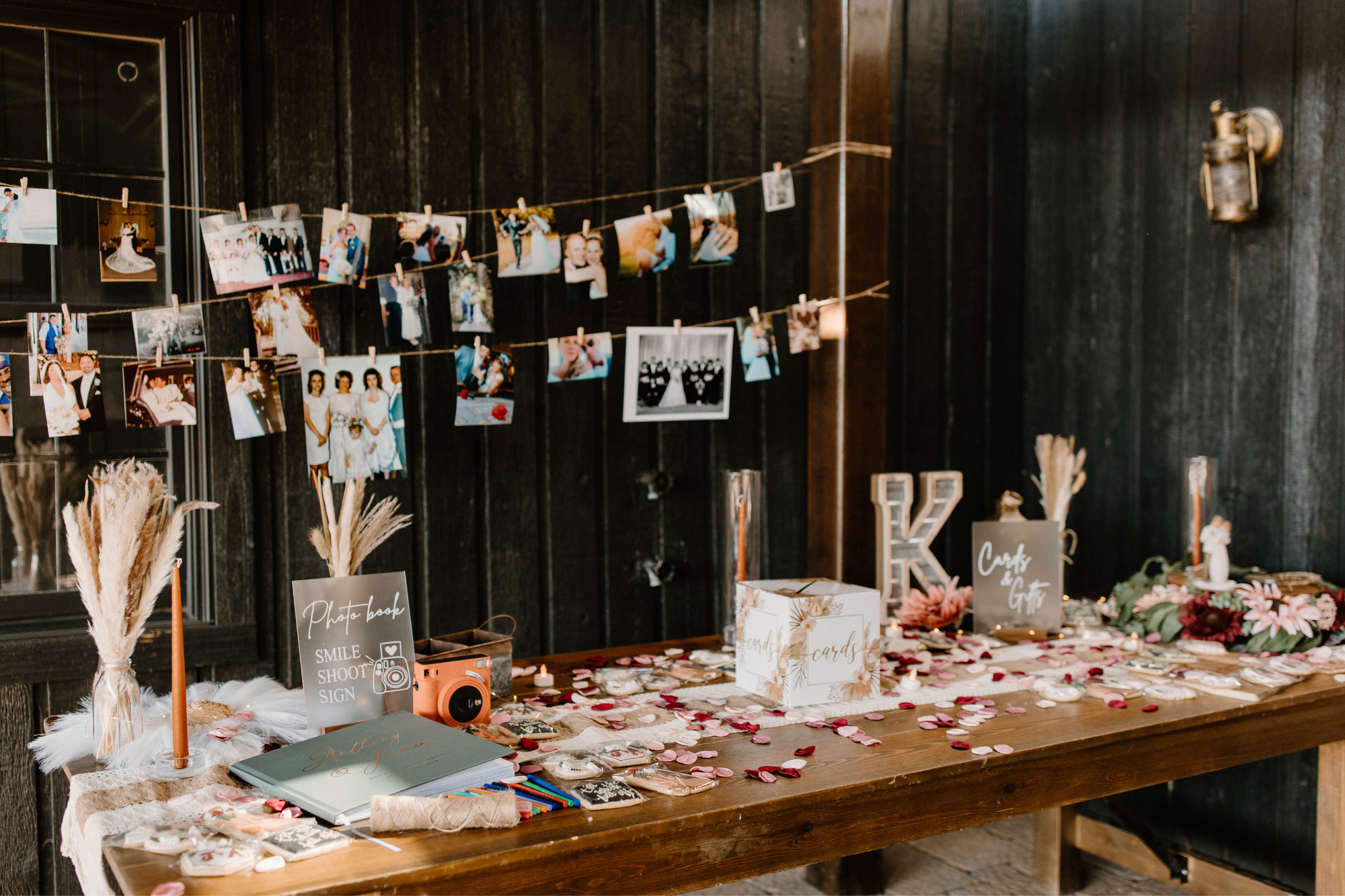 Polaroid pictures hung on string over bridal guestbook table at wedding reception