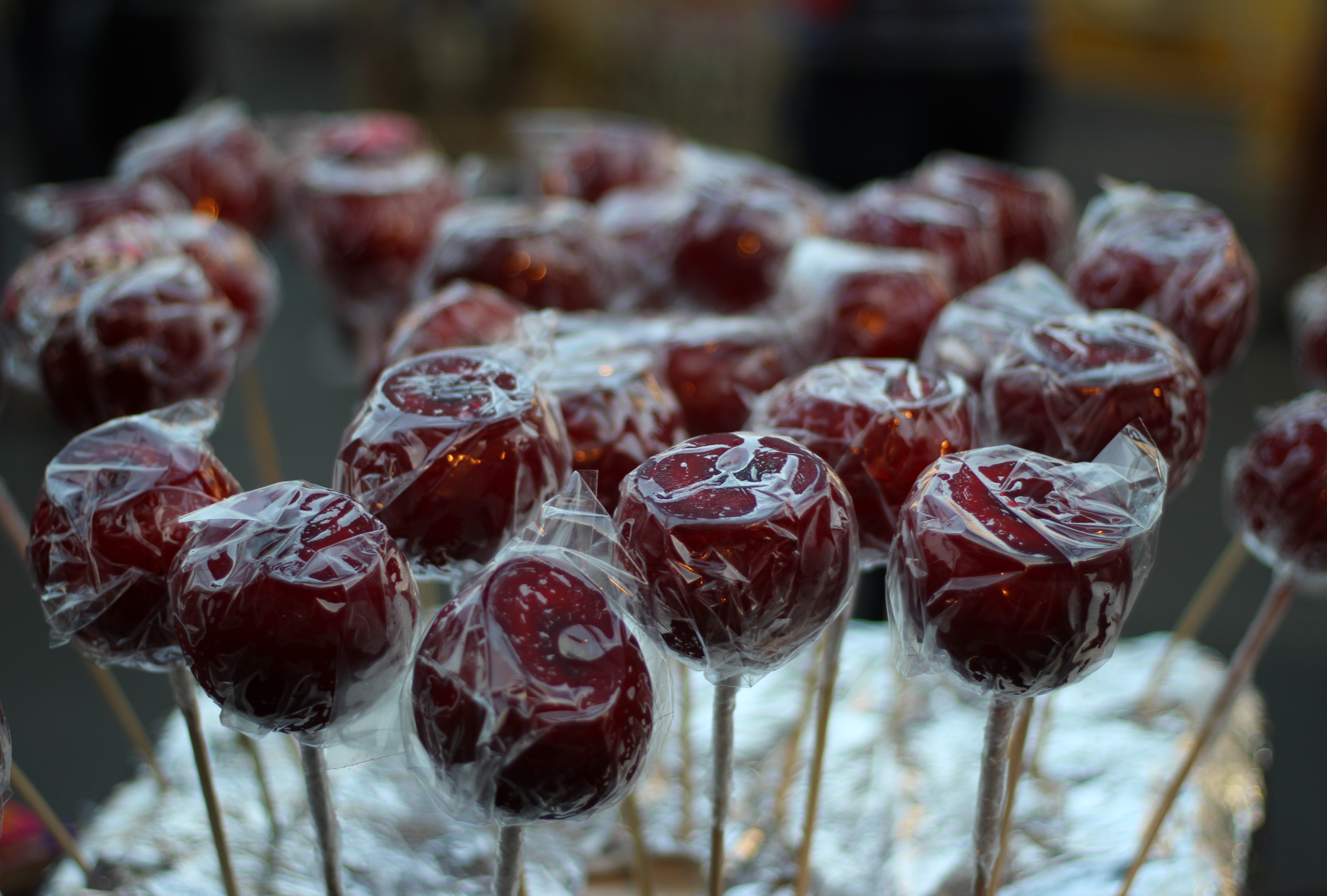 Dark lighting over selection of individually clear wrapped red candy apples