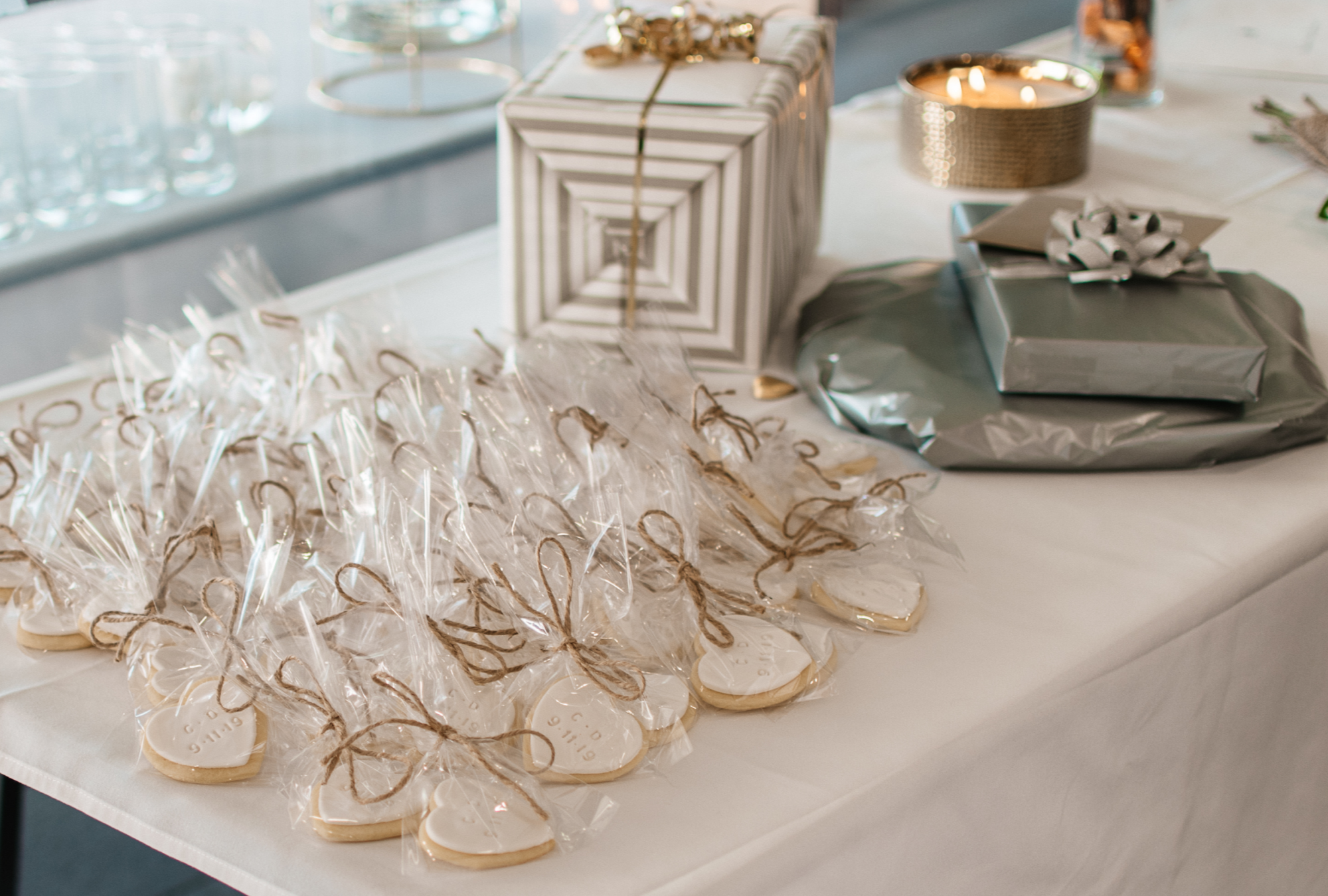 White table with white and gold presents and iced monogram cookies for wedding