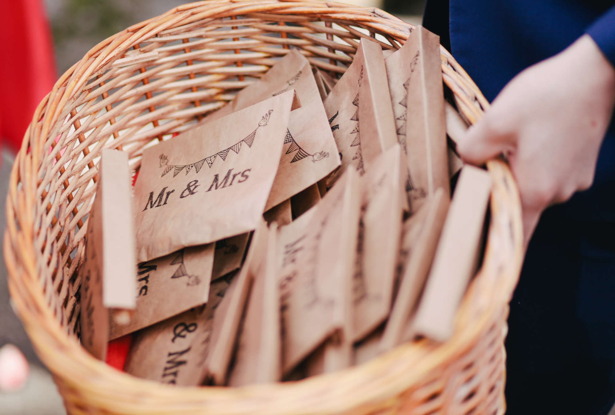 Woven basket being lifted with lots of brown envelopes labelled Mr & Mrs in black writing