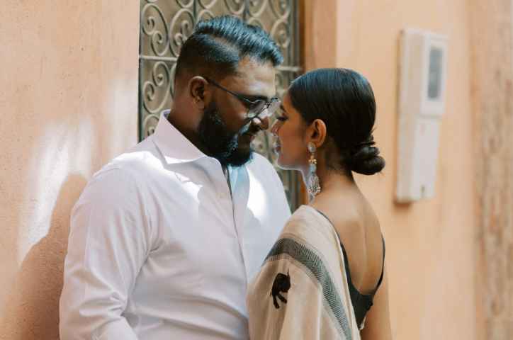 Indian couple close together against an orange wall